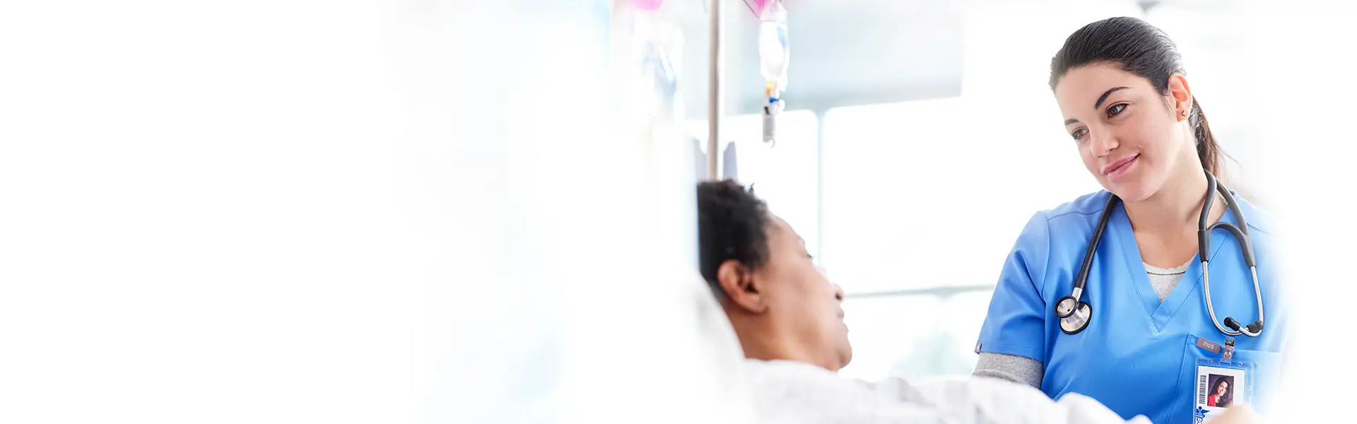 Nurse with stethoscope looking down at her patient.